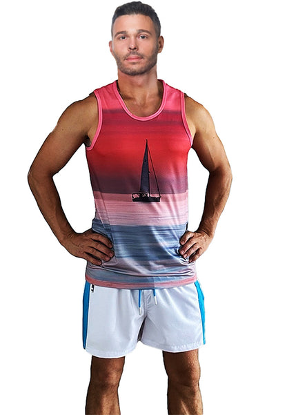 A person stands confidently with hands on hips, wearing a sleeveless Breathable Beach tank top "Sailboat" by BWET Swimwear featuring a gradient sunset design with a sailboat silhouette and white shorts with blue side stripes. The minimalist background is plain white.